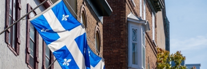 Province of Quebec flag hanging from side of a building.