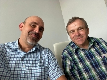 Two men in plaid shirts sitting together smile