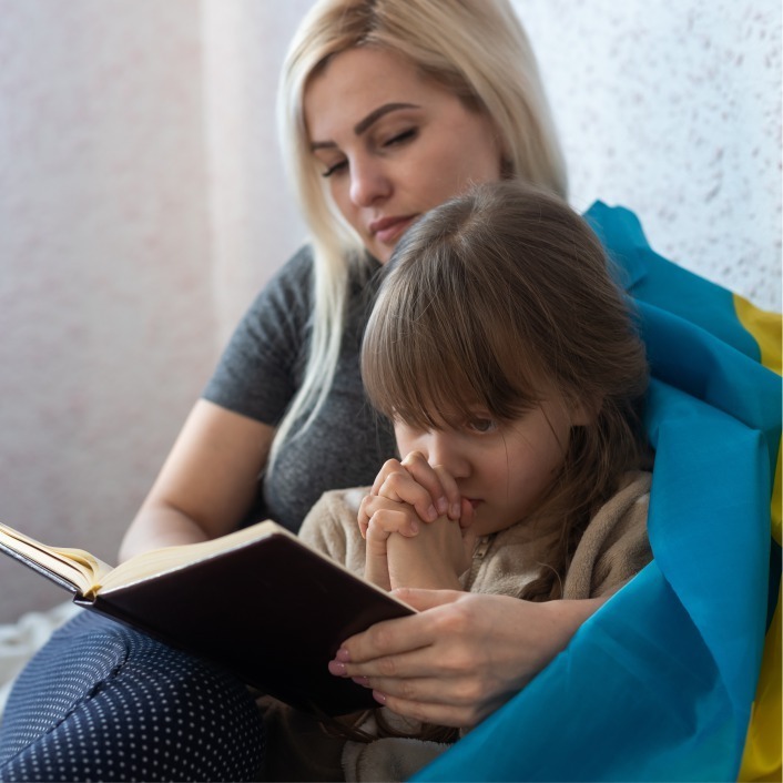 A blond woman sitting with her young daughter reading a book