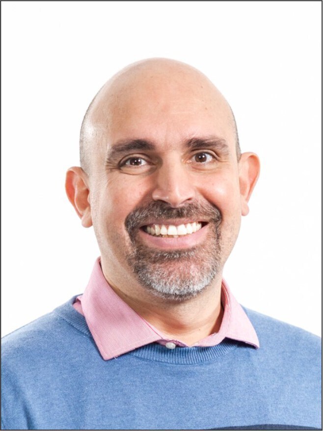 Smiling man in front of red brick wall