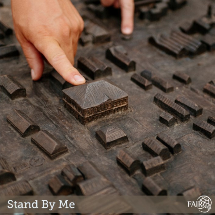 Fingers pointing to 3d diagram of buildings and houses on a brown board