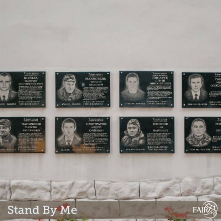 Eight photos on a white wall of those who have died in the war in Ukraine