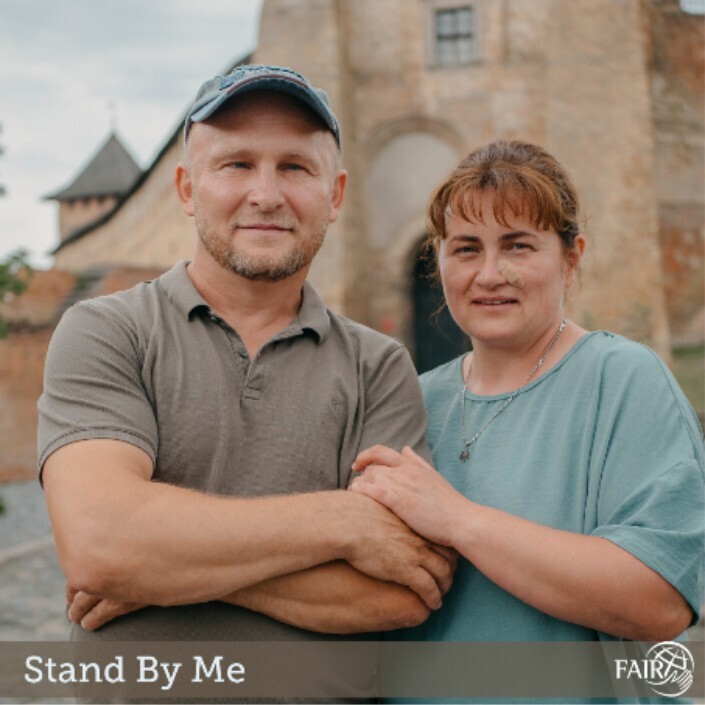 A middle-aged husband and wife standing in front of a church building.