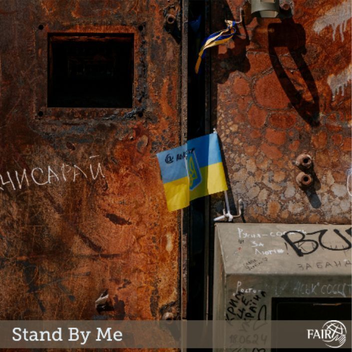 A grafiti-filled wall with rust marks and a small Ukrainian flag.