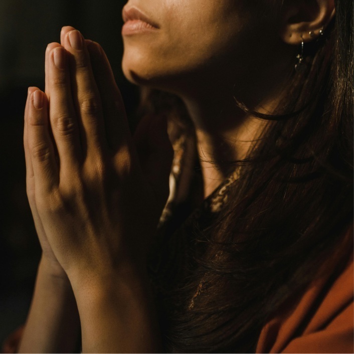 African American woman with hands held up to her face in a praying manner.