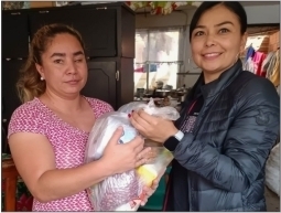 Woman giving a bag of much needed food and other essentials to a woman