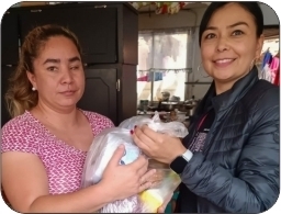 Woman giving a bag of much needed food and other essentials to a woman