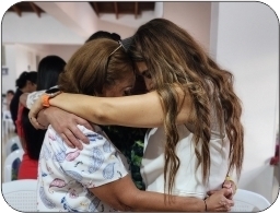 Three women gathered together in a circle hugging one another in prayer